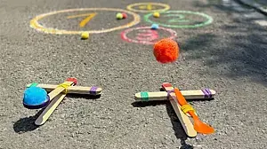 © Ina Kerckhoff Zwei selbstgebaute Katapulte aus Holzstäbchen und Haushaltsgummis: Von einem fliegt ein Schwämmchen durch die Luft Richtung Kreide-Kreise auf der Straße.