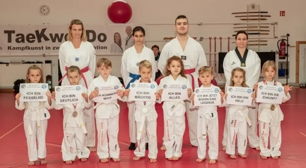 © André Ulrich Kinder in Trainingskleidung halten Schilder mit Botschaften wie "Ich bin ein Held." hoch.