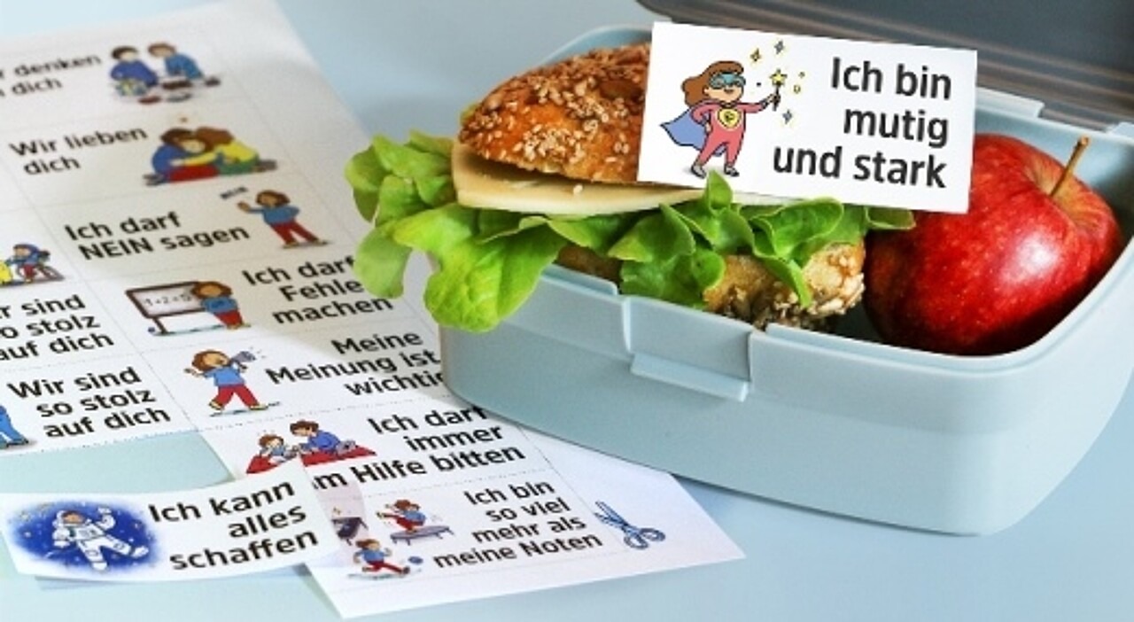 „Ich bin mutig und stark“ ist auf der Botschaft zu lesen, die auf einem mit Käse und Salat belegten Brötchen in einer geöffneten Brotdose liegt.