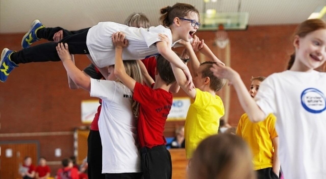 Ein Kind wird auf auf den Händen vieler Kinder getragen.