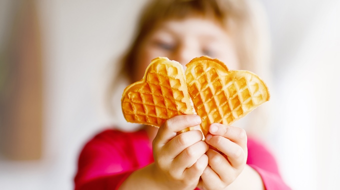 Ein Kind hält eine Waffel in die Kamera